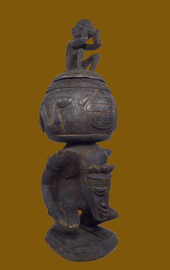 DOGON ANTHROPOMORPHIC CEREMONIAL CONTAINER WITH LID: A tall carved wooden vessel with fitted lid, decorated with a monkey chewing a root, and the body of the vessel on top is decorated with animal forms, and the entire piece is supported by a highly sty