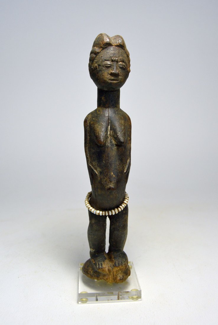 MINIATURE BAULE FEMALE IDOL AFRICAN ART: A lovely old carved wooden female effigy with stylized coiffure, hands held down along the torso, protruding navel and old glass beads around the waist. Obvious weathering and handling suggest ritual 