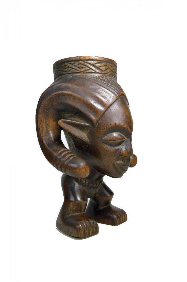KUBA PALM WINE CUP WITH RAM HORNS: A finely crafted wooden beaker with ancestor face and large ram horns as cup handles on large feet. Kuba peoples, Congo, Africa. The Kuba cup measures 9 inches tall x 5.25 inches wide.