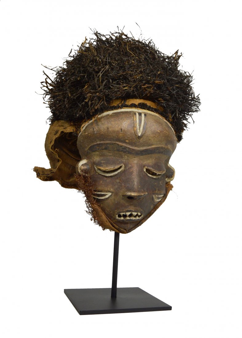 Pende mask with full Coiffure Collected in situ 1972: A carved wooden mask accented with kaolin clay pigments, stylized face and woven grass coiffure. Pende peoples, Congo, Africa. The mask itself measures 12 x 9 inches. A durable display stand can be in