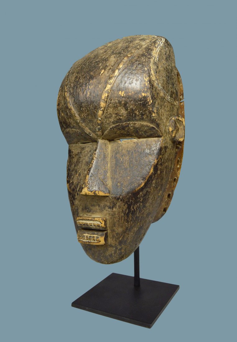A Fierce Dan Bete African mask: Old wooden dance mask with bold facial features and rasied linear designs, painted teeth with small slit eyes. Bete peoples, Dan Complex of Tribes, Ivory Coast, West Africa. The mask measures 13 x 7.5