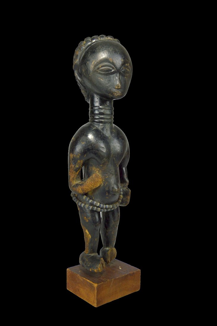 Ancient Lady of the Lagoons Attie Sculpture: A very old and interesting carved wooden female effigy with well worn and well handled features, and shown holding a woman's satchel. The sculpture has a ringed neck , a symbol of status among the loc