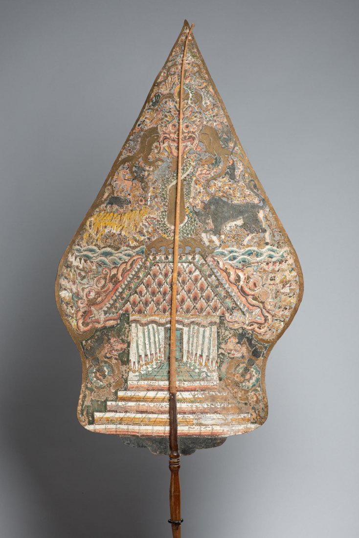 Antique Shadow Puppet from Java, Indonesia: The gunungan (Javanese \"mountain\"), also known as kayon or kayonan from kayu, \"wood\" or \"tree\" Shadow Puppet or play piece. Buffalo hide, pigments, wood. H: 40”, W: 17”. Early to mid 20th ce