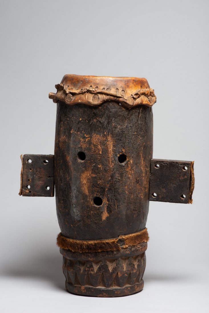 A very Old wooden drum: An old wooden drum with stylized face and appendages and stretched animal hide drum head. H: 20.5”, W (at ears): 14”, Dia: 10”. African. Provenance: Donated by a member of The Ethnic Arts counci