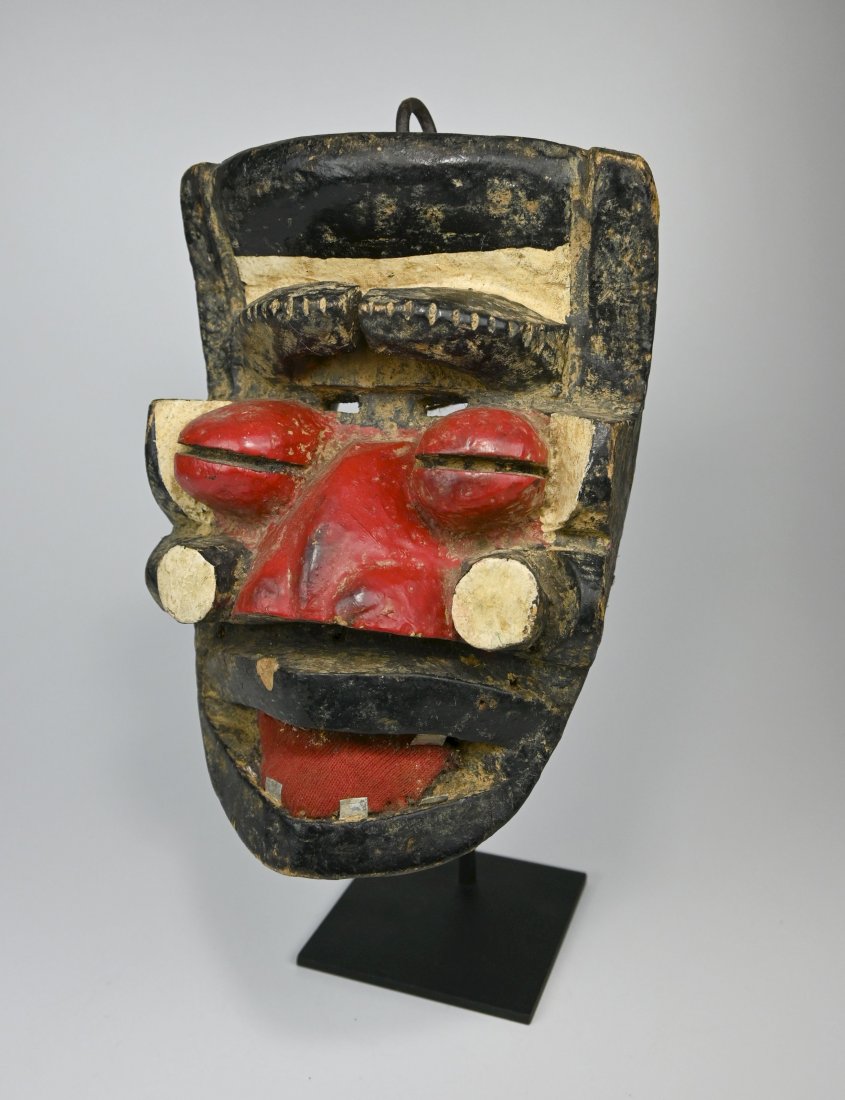 A Dramatic Dan Guere Mask Ex Dr Healy Estate NY: A bold carved wooden dance mask accented with red and white paint and embellished with inset metal teeth, metal spike and red textile. Guere / Gere , We peoples Ethnic group within the Dan complex of 