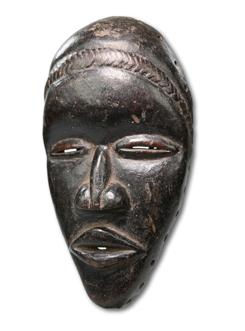 A Dan African Mask: Carved wooden mask with well handled and worn surface, thick black pigmented surface and signs of handling and field use. Dan peoples, Ivory Coast, West Africa. The mask measures 9.5 x 5.25 inches.