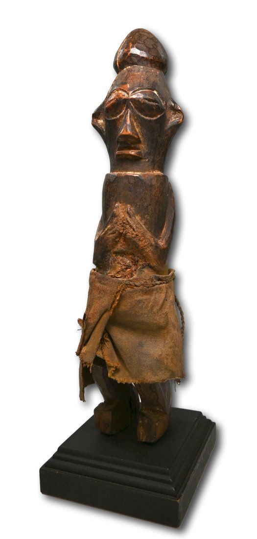 A Suku Idol: A Carved wooden effigy with highly stylized facial treatment, flared ears, large oval eyes and hands in prayer like pose. Suku peoples, DRC/ Congo, central Africa. The idol measures 12 inches tall ( 1