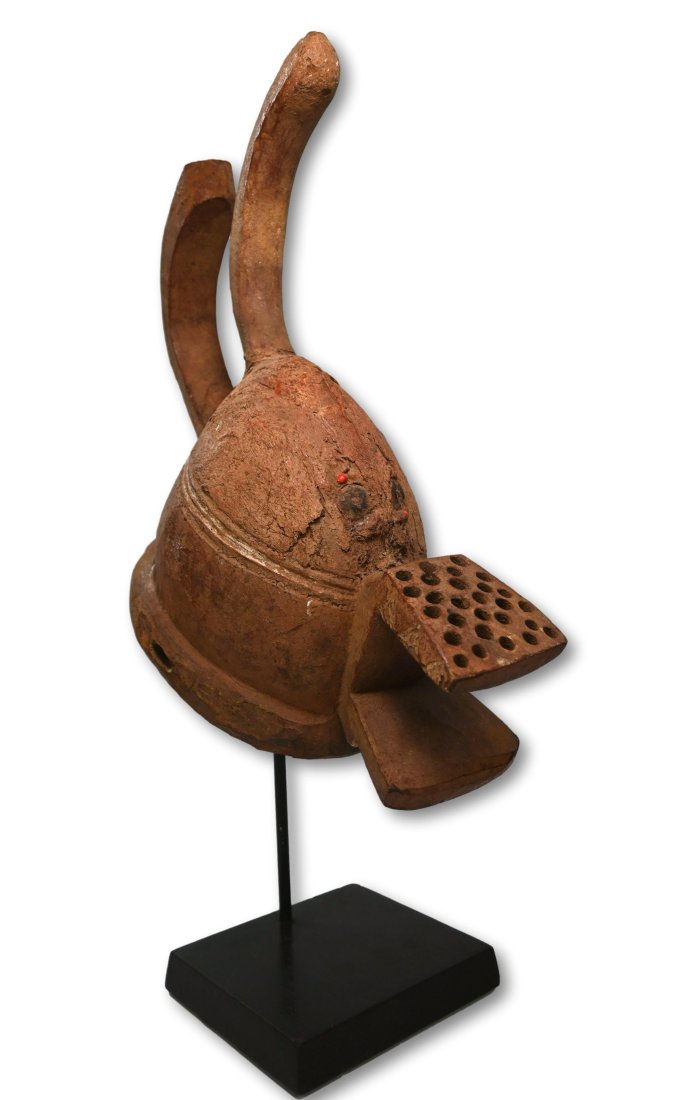 A Mama Bushcow Mask Ex Prof. Gould Collection: A highly stylized wooden helmet /cap mask with two horn like appendages and embellished with a reddish mineral pigment and abrus seeds. Mama peoples, Nigeria, Africa. The mask itself is 15 inches tall