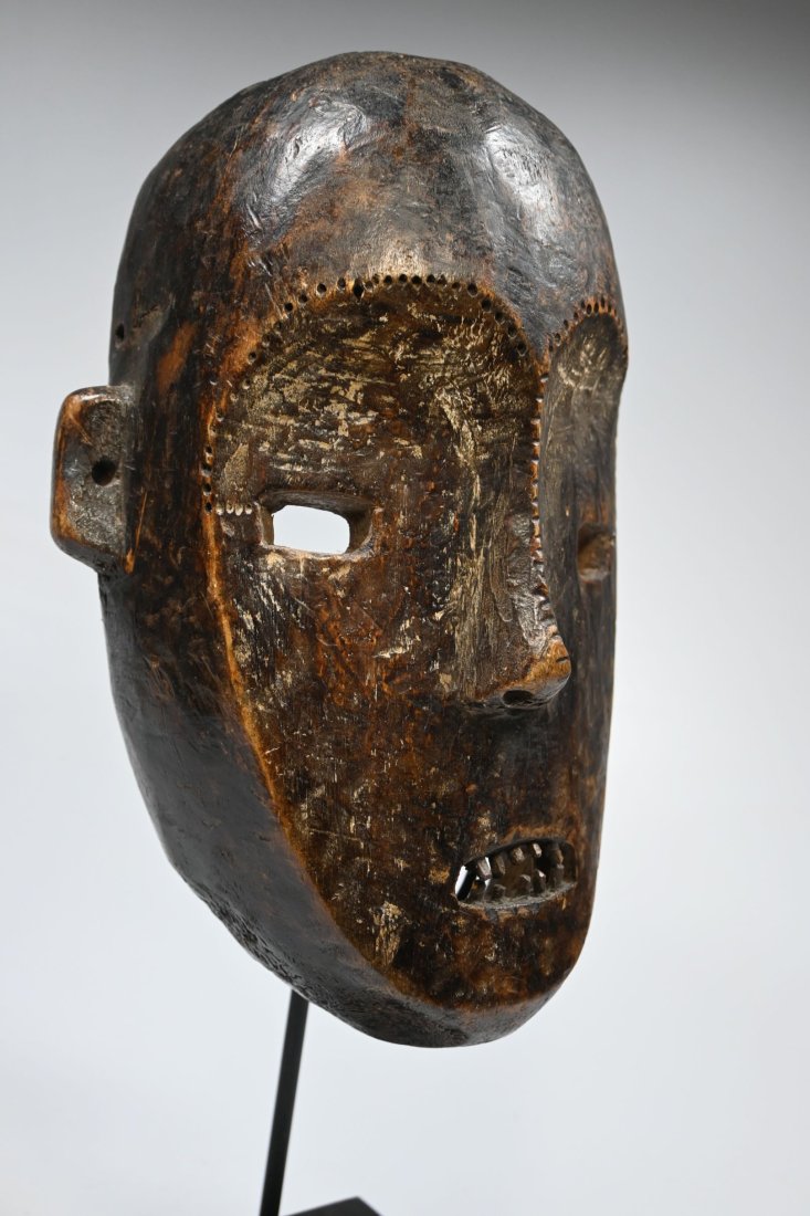 A Ngbaka African mask: A carved wood face mask with open work eyes, inset wooden teeth, remains of kaolin clay around the eyes and a well handled and worn surface patina. Ngbaka peoples, DRC/ Congo, central Africa. The mask