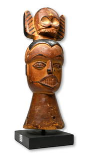 A Fine Ibibio Dance Crest Ex Zemanek Auctions: A carved wooden janus dance crest with stylized human skull atop and two anthropomorphic faces rendered in classic style with a well handled honey colored patina. The Crest measures 14 inches tall. 16