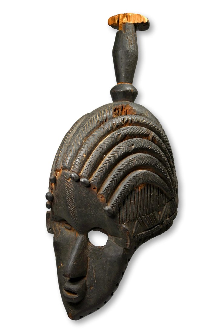A Rare Bassa Semi-Helmet Mask: A Rare Old Carved wooden helmet mask with stylized coiffure, classic bassa style facial features, a tall central finial and a unique treatment to the open eyes of the mask, with one eye worked and wor