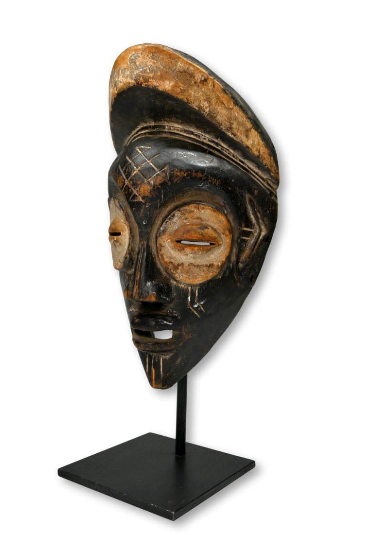 A Fine Mbagani Mask Ex Kahan Gallery: A carved wooden mask with enlarged eyes accented with kaolin clay pigment and an overall stylized face and form. Note the deep patina from handling. Mbagani peoples, DRC/ Congo, central Africa. The ma