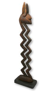 A Bamana Zig Zag Headdress: A tall carved wooden zoomorphic form in abstract style with an antelope head atop a highly stylized body. The zigzag motif has been interpreted by some scholars of Bamana culture as having great symbo