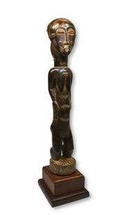 A Fine Baule Female Effigy Ex Banks Collection: A carved wooden female idol with an unusual treatment to the face and head, finely carved coiffure, raised scar designs. Baule peoples, Ivory Coast, West Africa. The sculpture measures 17.5 x 3.5