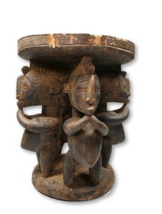 A Baga Stool: Carved from a very heavy dense wood and featuring 4 stylized Nimba sculptures as the central support, incised linear designs. Baga peoples, Guinea, West Africa. The Stool measures 15.5 inches tall x 1