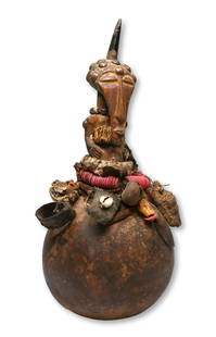 A Kusu Magic Gourd Rattle Fetish Ex Simmons Collection: A unusual carved wooden magic power idol embedded into a Gourd and embellished with beads, seeds, goat horns, bells and various woven fibers. Kusu peoples, DRC/ Congo, central Africa. The gourd fetish