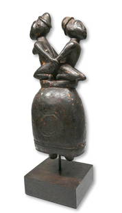 A Bakongo Ritual wooden Bell: A carved wooden bell or gong with two strikers inside, and male and female effigy figures faced in opposite directions on top. Elaborately carved bells such as this one, called madibu or sing dibu,