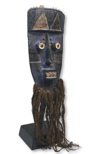 A Grebo African Mask: A carved wooden mask in a highly stylized anthropomorphic form, embellished with blue pigments and kaolin clay earthen paints, tubular eyes and woven plant fiber bead. Grebo peoples, Liberia, West Afr