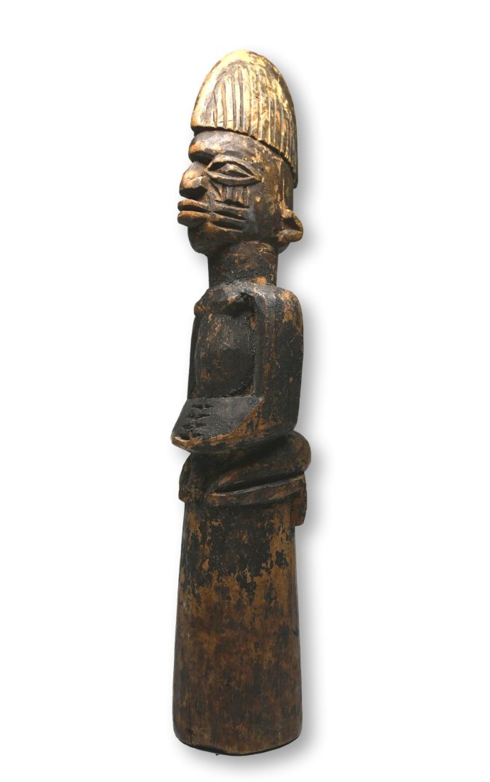 Old Yoruba Kneeling Devotee Cult Idol: A carved wooden kneeling devotee with strong facial treatment and bold form, with signs of handling. Such a sculpture is likely part of a shrine as kneeling figures, often nude, are common in Yoruba r