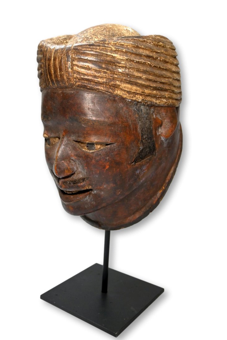 A Makonde Dance Mask of a Arab Trader: Old carved wooden helmet style mask carved in the image of an Arab Trader, with human hair sideburns, mustache and hair on scalp and carved turban. Makonde peoples, Mozambique, Africa. The mask measur