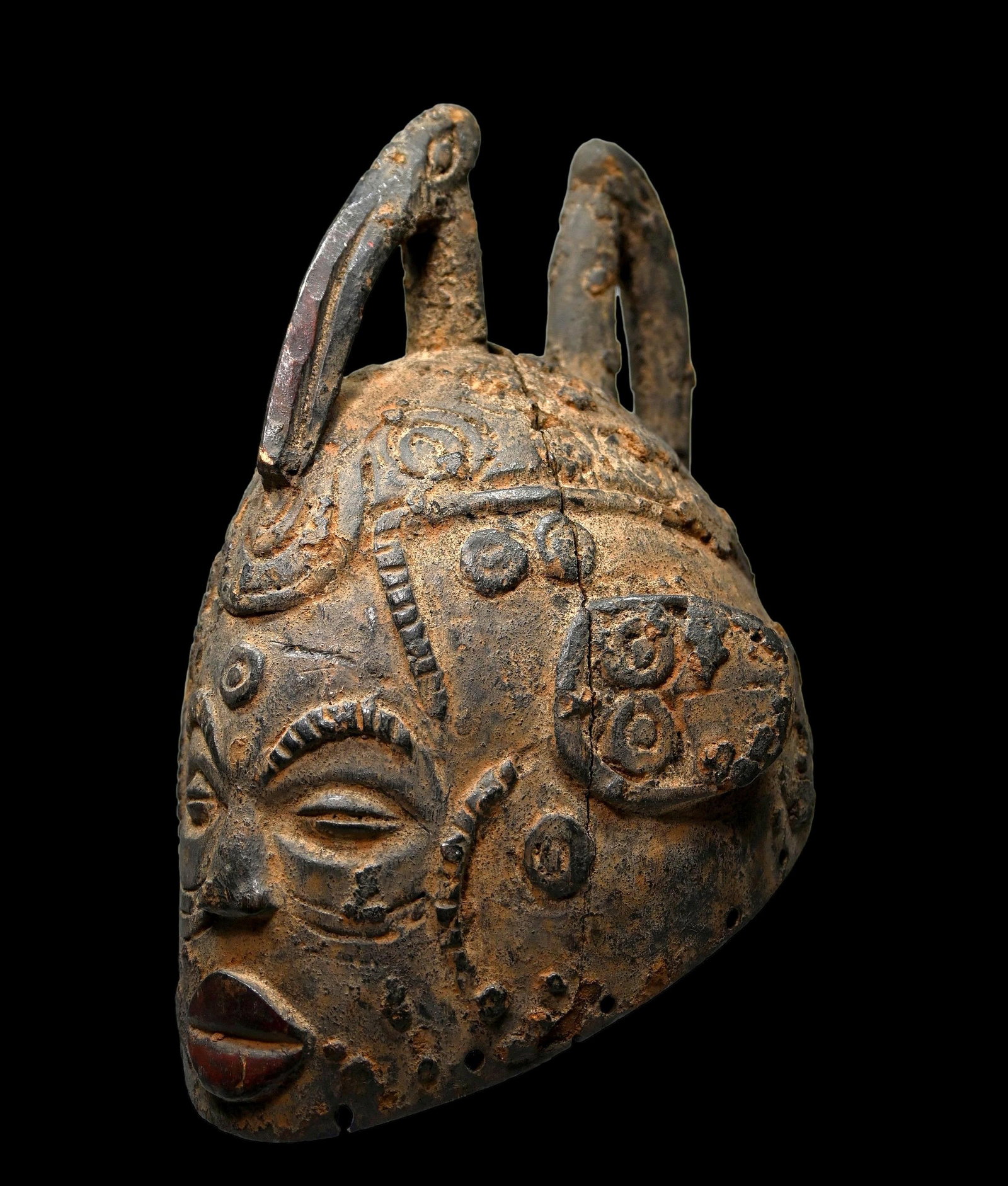 Old Idoma Mask with Avian Finials Ex Berg En Dal Museum: This is a very old and interesting wooden helmet style mask with raised and incised coffire and scar designs, along with two long beaked avian finials, encrusted surface and signs of field use. The ma