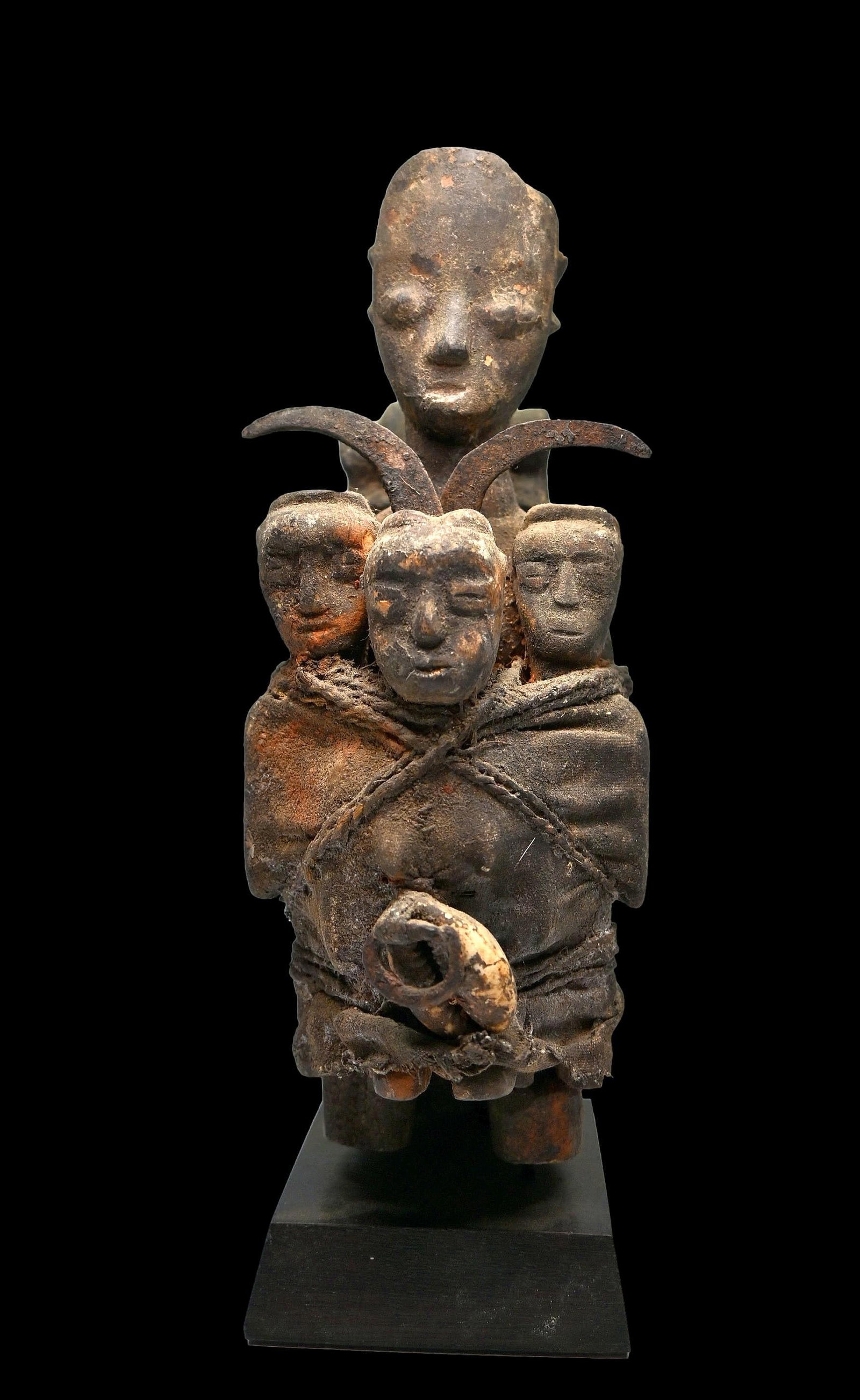 Ewe Shrine Fetish with Spirit Idols and Bones Ex Daniel Simmons collection: A carved wooden shrine idol bound to 3 other spirit figures, a large animal bone and iron symbols of the Vodoun God of thunder, hevioso. The Idol measures 9.5 inches tall on its custom wooden base. Ew