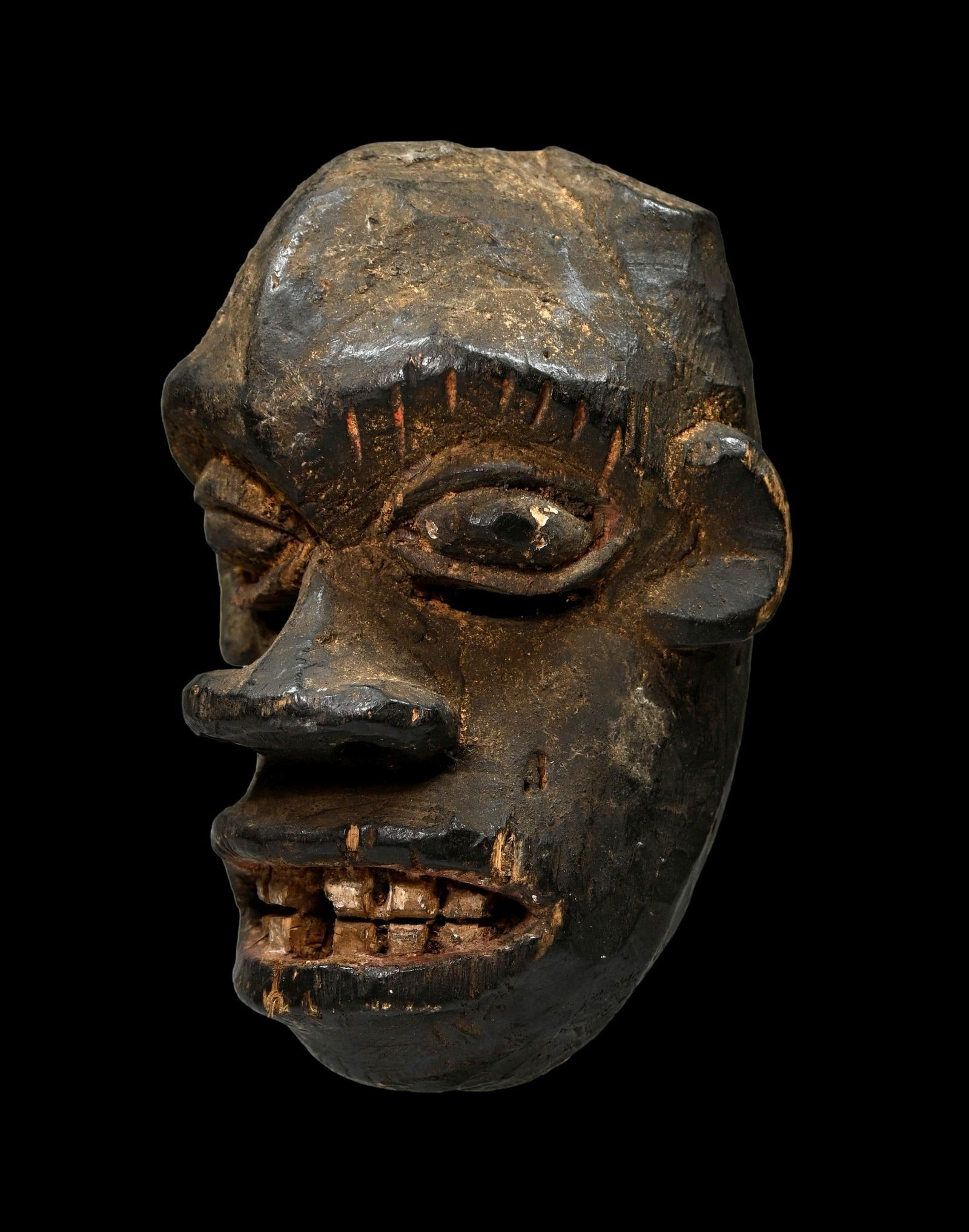 A Ibibio Ekpo Mask Ex Turner Collection: A carved wooden ceremonial mask with art brut aggressive facial features, carved wooden teeth, curled lips, large flaring nose and eyes accented with kaolin clay pigments. Masks such as this from the