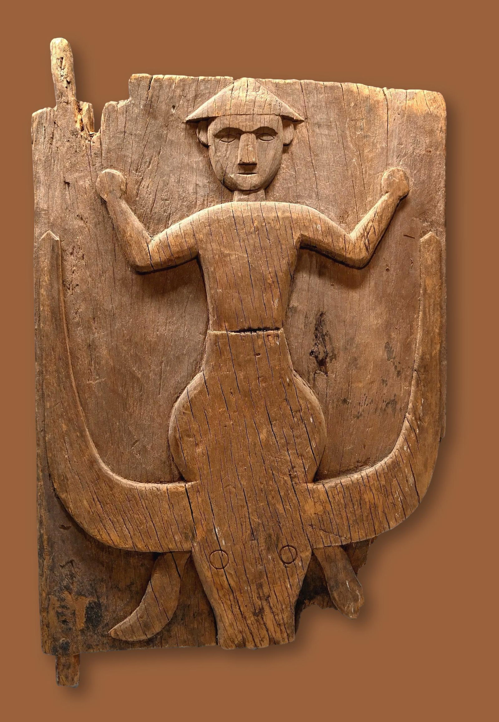 A Tana Toraja Granary Door: A weathered wooden door with an ancestor figure carved in relief shown atop a Buffalo effigy. This antique example was carved from nangka wood (jackfruit) with an aged and weathered patina. Buffalo we