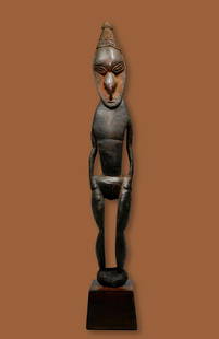 A Fine Lower Sepik Sculpture: a Fine Lower Sepik figure. Lower Sepik/Ramu. Madang province, Papua New Guinea. The figure of characteristic form with pointed coif and concave face, the body elongated with thin arms carved akimbo,
