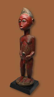 A Red Baule Colon Sculpture Ex Endicott Collection: A charming carved wooden female effigy painted red with highly stylized facial features and form, likely dating from the Colonial era, Baule peoples, Ivory Coast, West Africa. The Sculpture measures