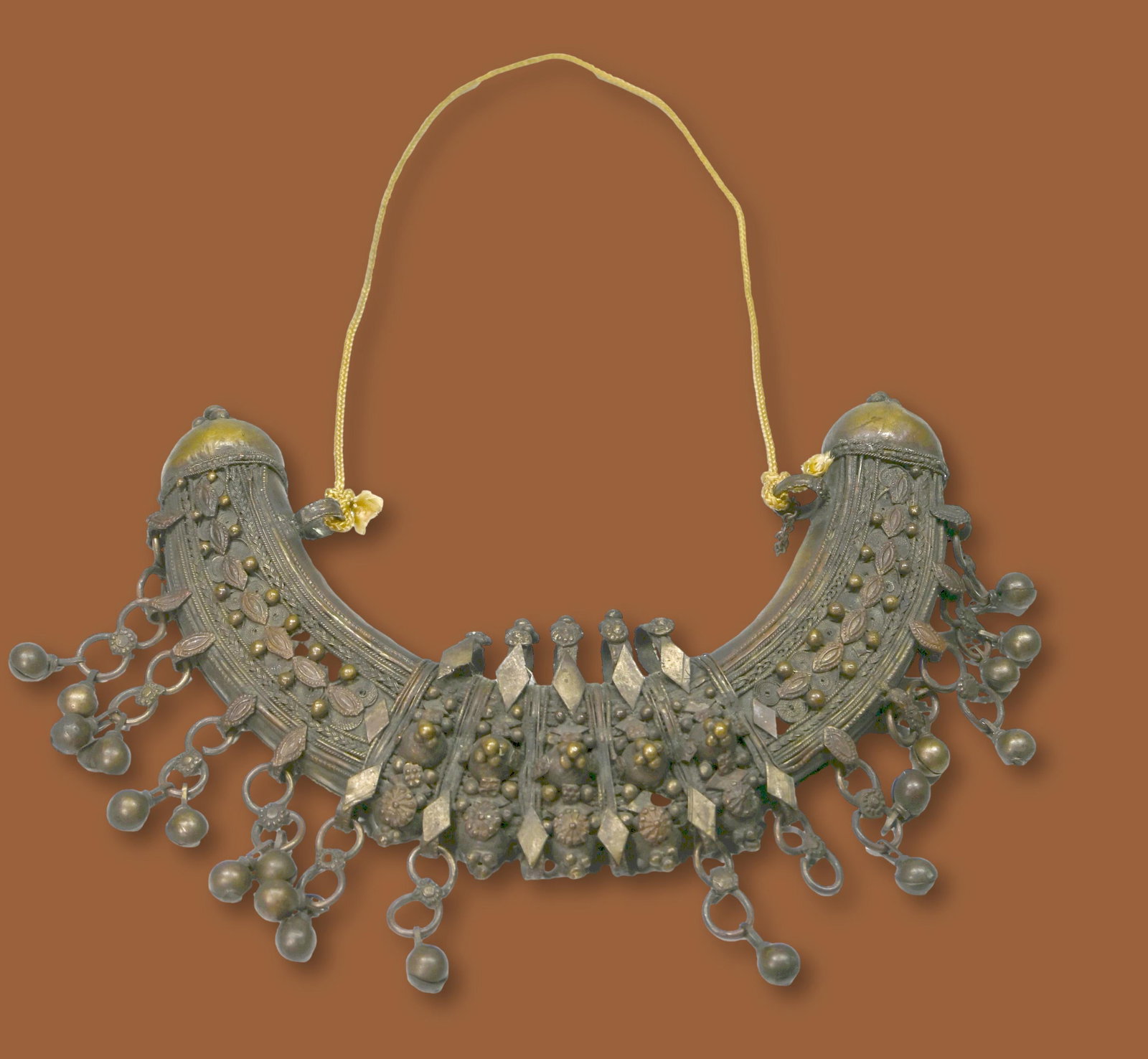 Antique Somalian Tribal Necklace: A very fine 19th century women's silver necklace with filigree motifs and hanging bells. The Necklace measures 10 x 7 inches. An old cord is hung with the necklace but it is likely not the original. A