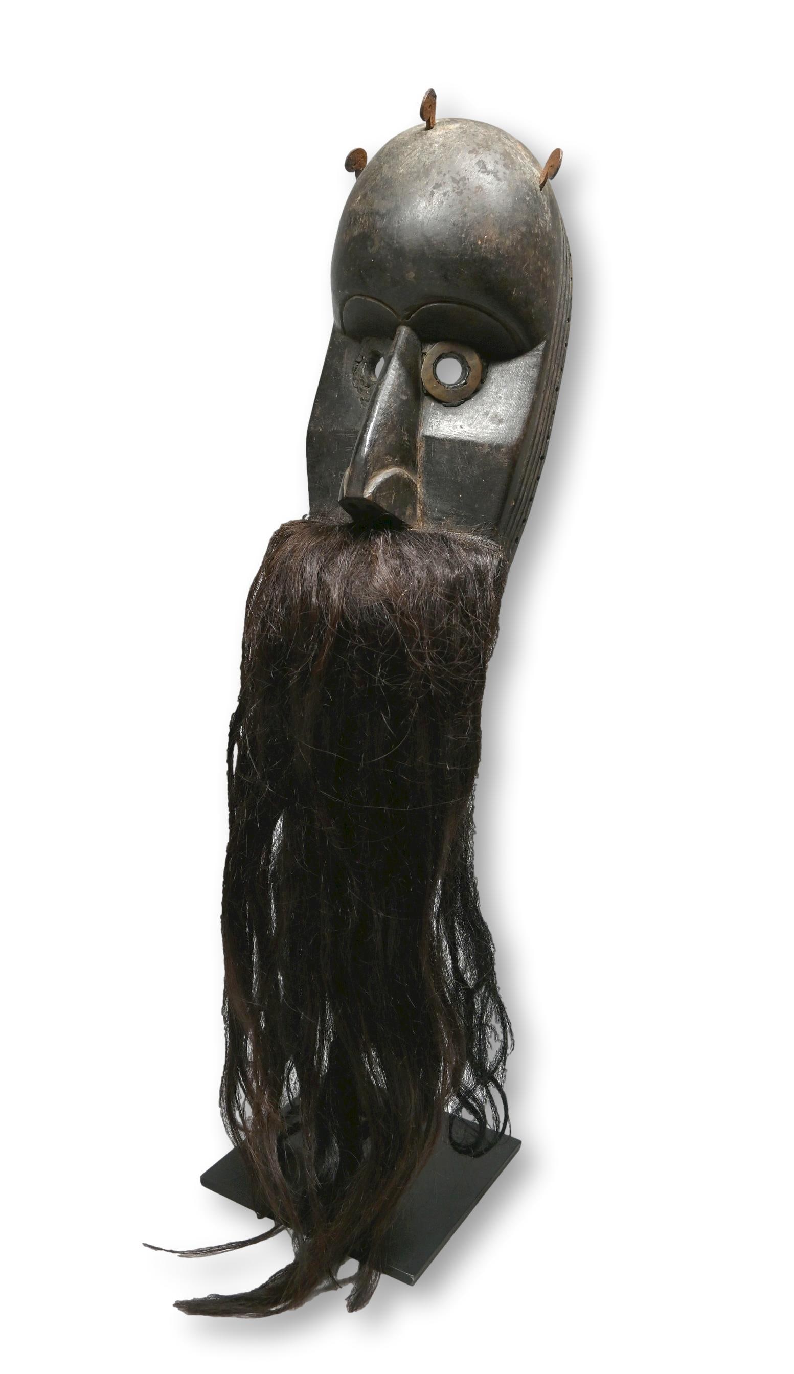 A Dan Loma Mask: Dan Loma Guerze mask with carved wooden face with round, metal accented eyes and forehead, arched brows carved in relief, nose with wide nostrils, incised linear designs and a articulated jaw covered