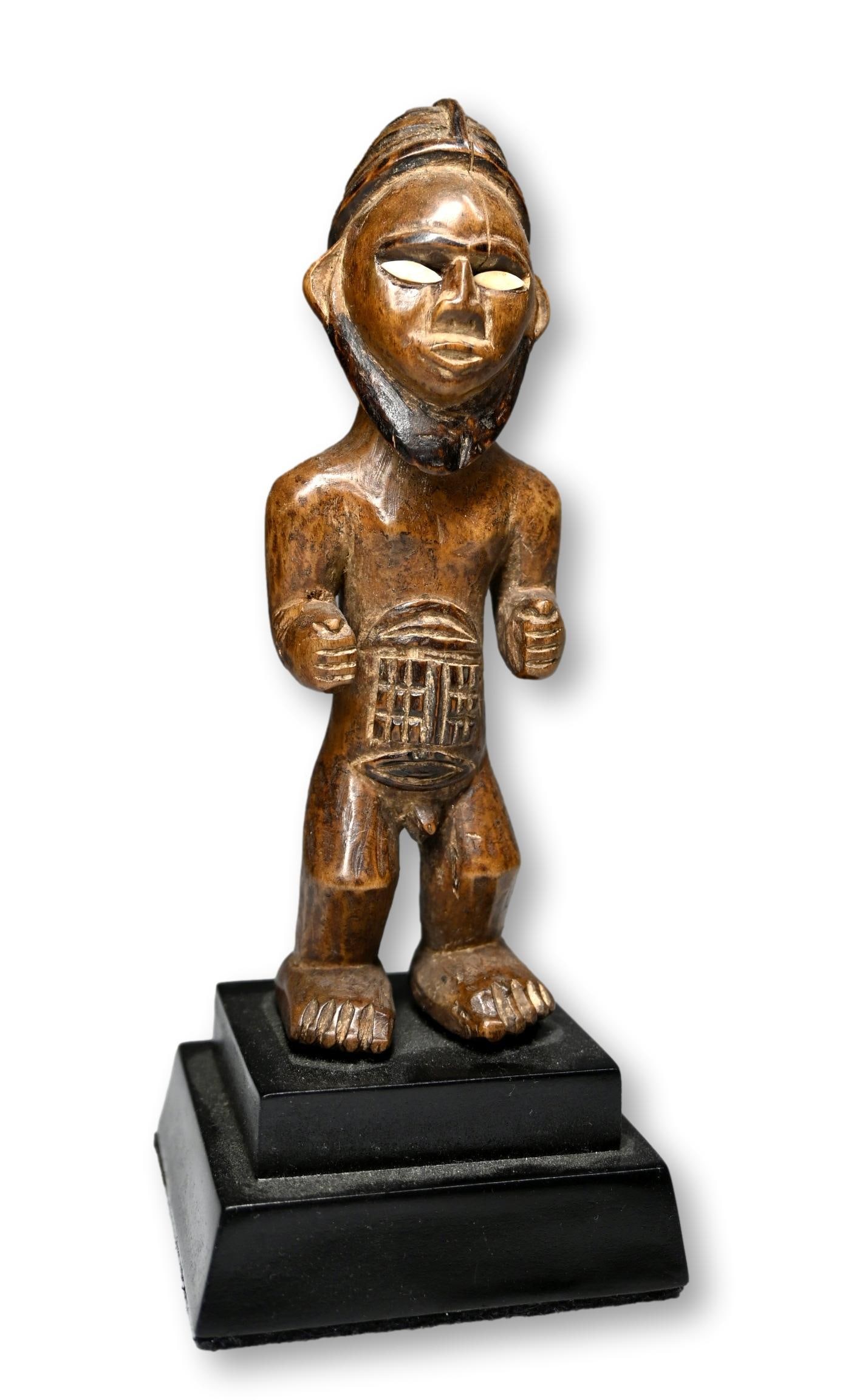 A Bembe Male Effigy: Carved wooden sculpture of a male with inset bone eyes, raised scar designs. Bembe peoples, DRC/ Congo, Africa. The sculpture measures 7.5 inches tall on wooden base. Provenance: Ex Daniel Simmons col