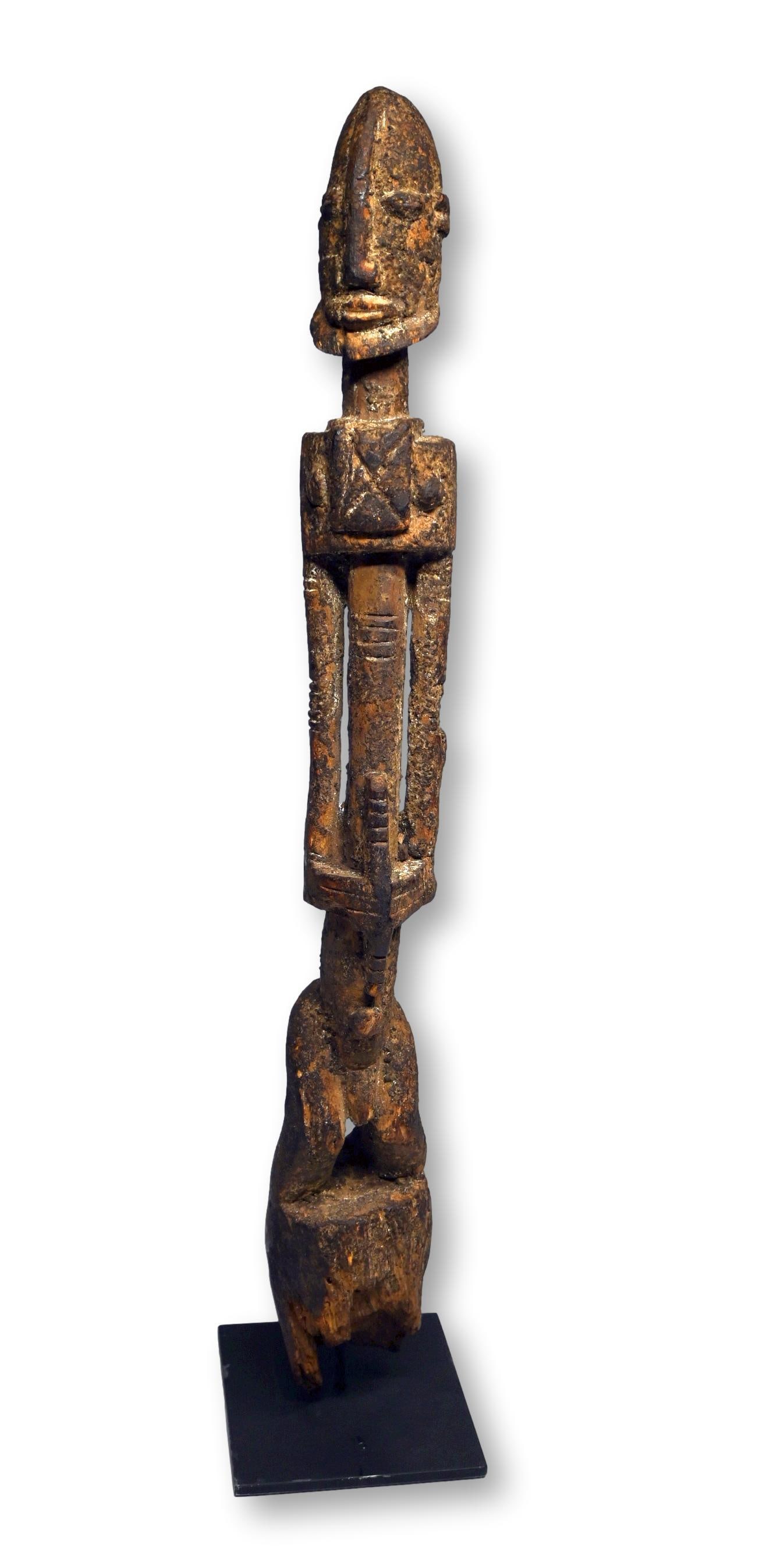 A Dogon Male Effigy: A tall weathered sculpture of a Tellum ancestor with highly stylized features as well as a heavily encrusted surface suggesting years of ceremonial use and ritual offerings. Dogon peoples, Mali, West 