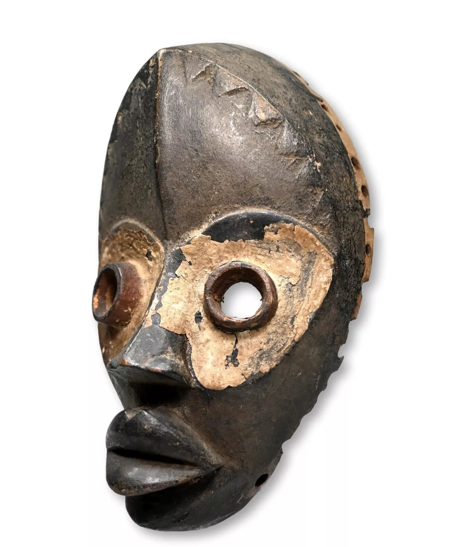 A Dan African Mask: A Carved wooden dance mask with well handled and worn surface, worn smooth incised linear designs and embellished with kaolin clay pigments around the eyes. Dan peoples, Ivory Coast, West Africa. The 