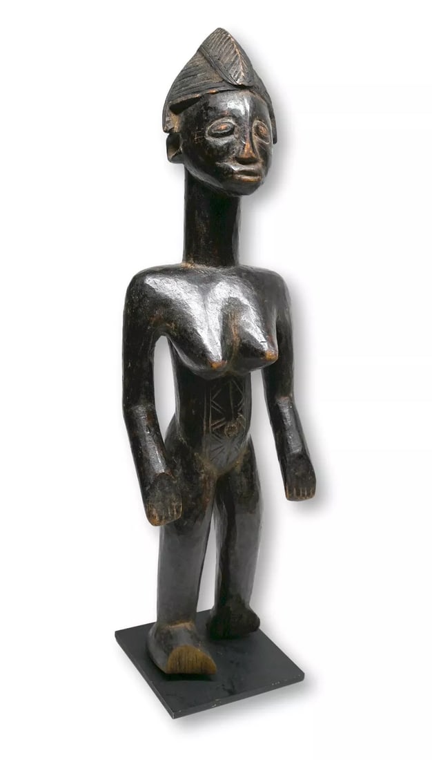 A Senufo Female Sculpture Ex Banks Collection: A finely carved female effigy with classic facial features, carved coiffure in traditional style and a deep well handled surface patina. Senufo peoples, Ivory Coast / Mali, West Africa. The sculpture 