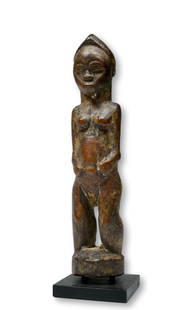 A Baule Divination Idol Ex Museum of African Art 1976: A small carved wooden female idol, likely part of a diviners assemblage or perhaps a shrine idol with layered surface suggesting years of field use as a ritual object. The sculpture measures 6 inches