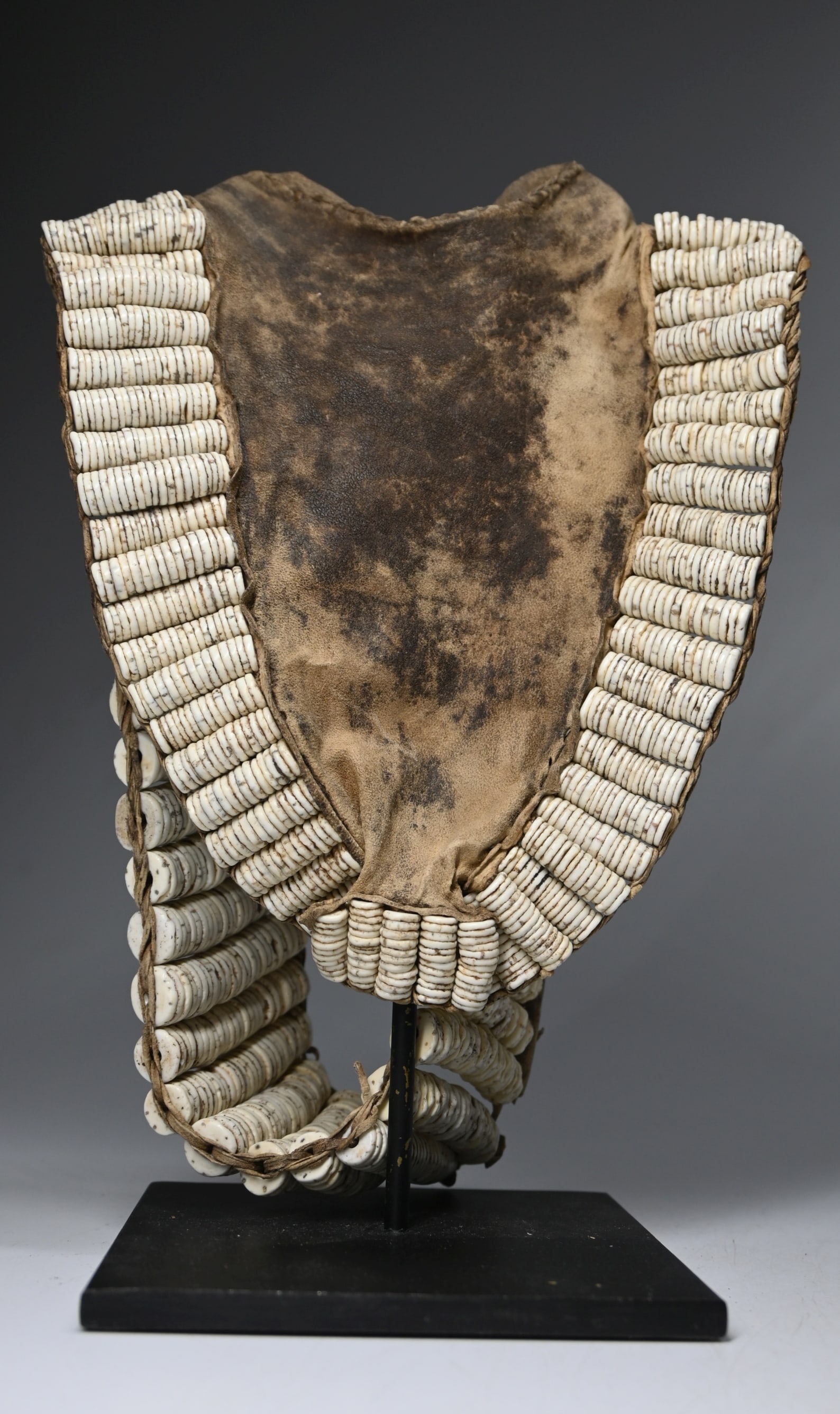Old Turkana Sex-Cache Ex Kahan Gallery: A old and interesting old sex cache or loin cloth adorned with ostrich shell beads and well used leather hide. The cloth measures 7.25 inches tall, 9.25 inches tall on custom display stand. Turkana pe