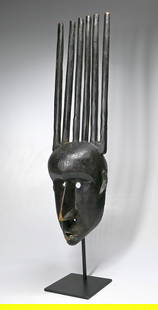 A Bamana Ntomo Society Mask: A carved wooden dance mask with a classic tall comb like structure above a stylized face with some incised designs, painted black and showing heavy use and wear on the interior. The Ntomo is one of ma