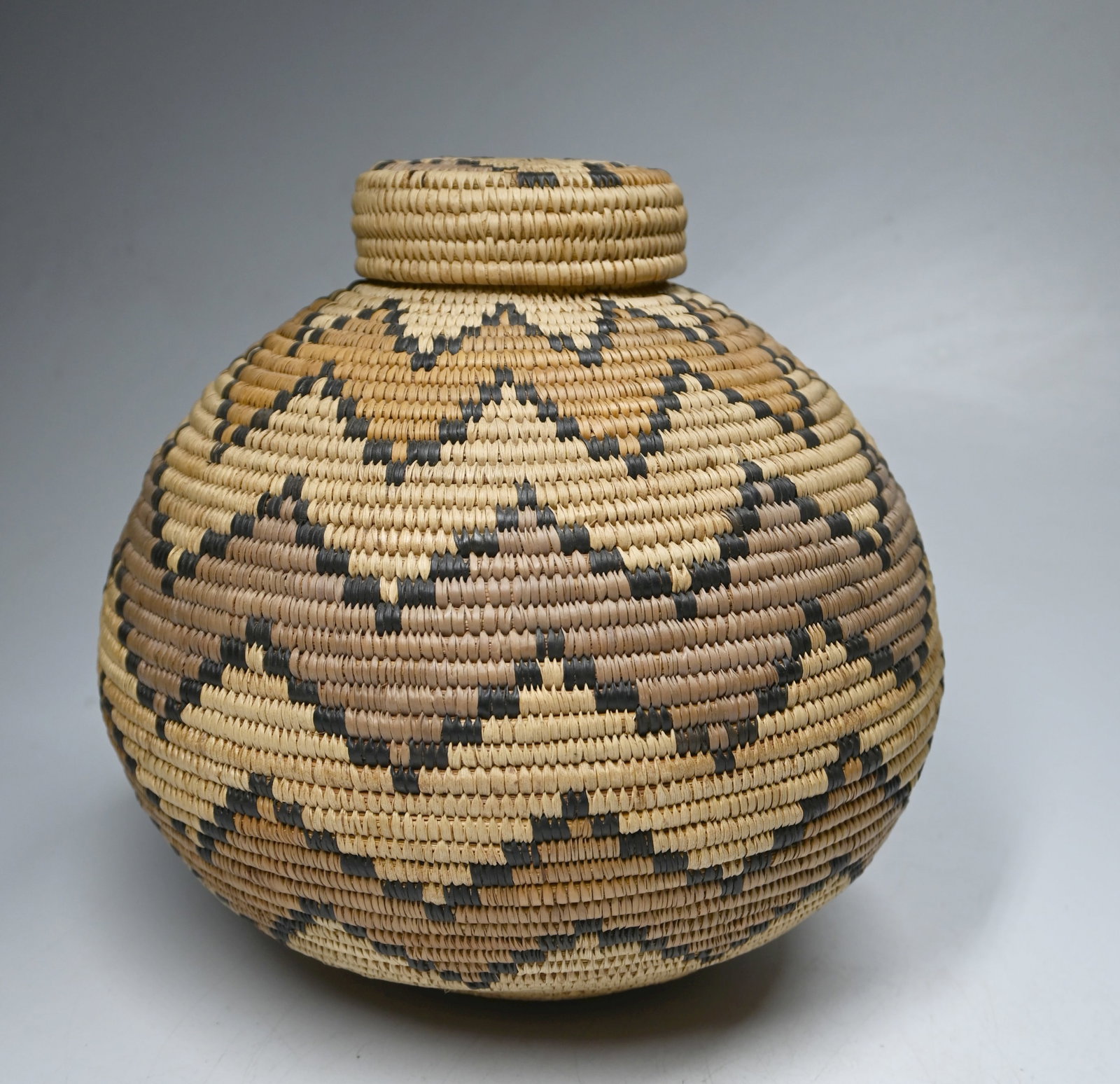 Lovely Zulu Basket Ex Cohen Collection: A Finely crafted Zulu Beer basket with tightly bound basketry decorated with linear designs and a tightly fitted lid. The basket measures 10 x 9.5 inches. A card inside states that it was made by Dina