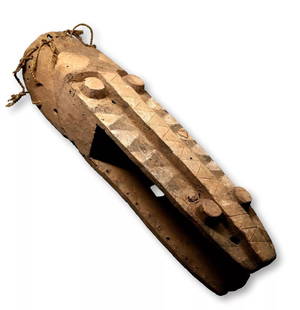 A Dogon Crocodile Mask: A Long carved wooden ceremonial mask known as “Waka Kakada” or Crocodile mask with raised eyes and snout , painted geometric designs, holes where wooden teeth were once inserted and remains