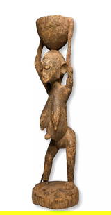 A Dogon Female Carrying a Burden Sculpture: A well weathered and worn sculpture of a female carrying a burden above her head, with very weathered and worn features, notably the arms , and even the bottom of one leg has a tribal repair with an