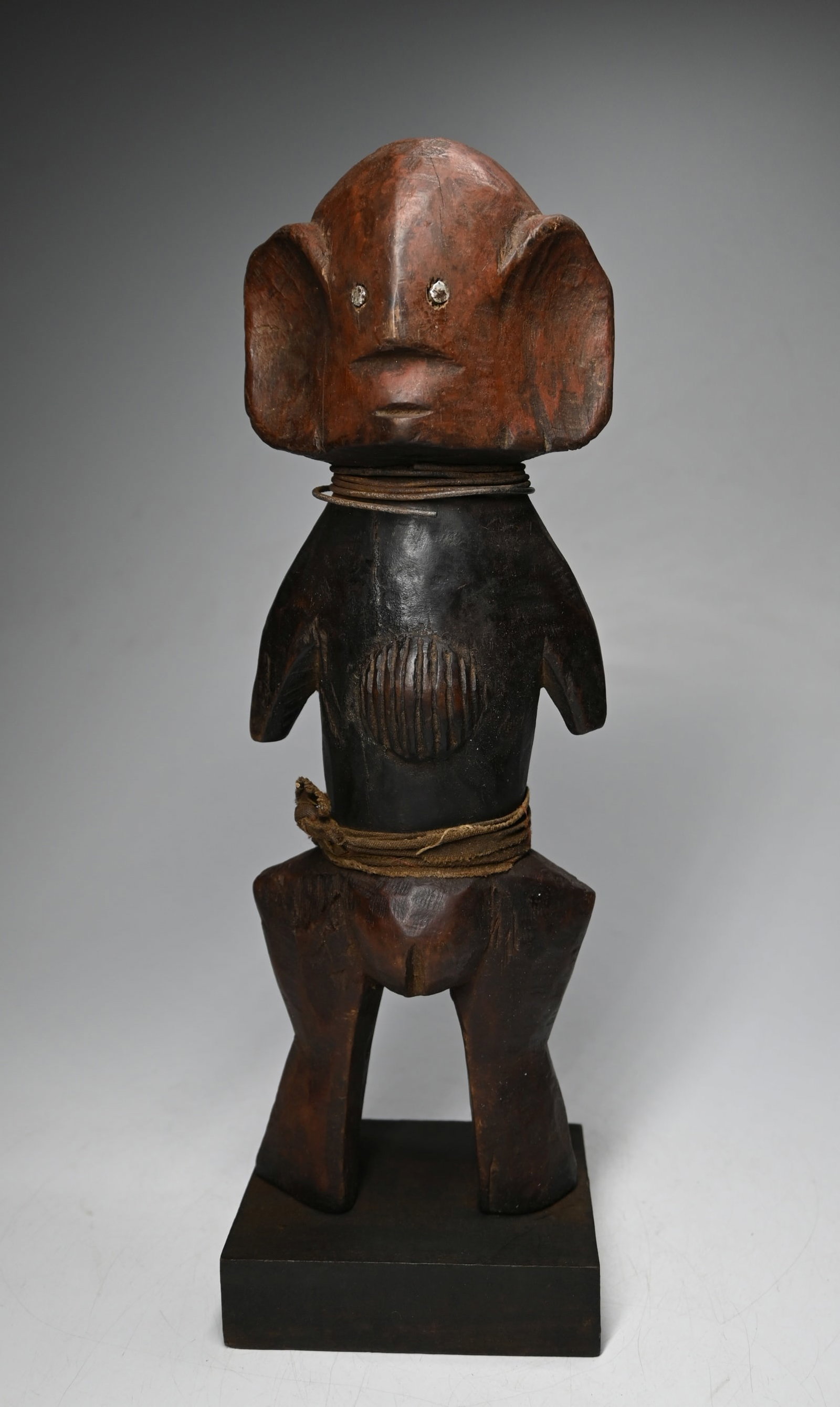 A Stylized Azande Female Effigy: A carved wooden female sculpture with highly stylized features, accented with reddish mineral pigments and incised linear designs. Azande peoples, DRC/ Congo, central Africa.