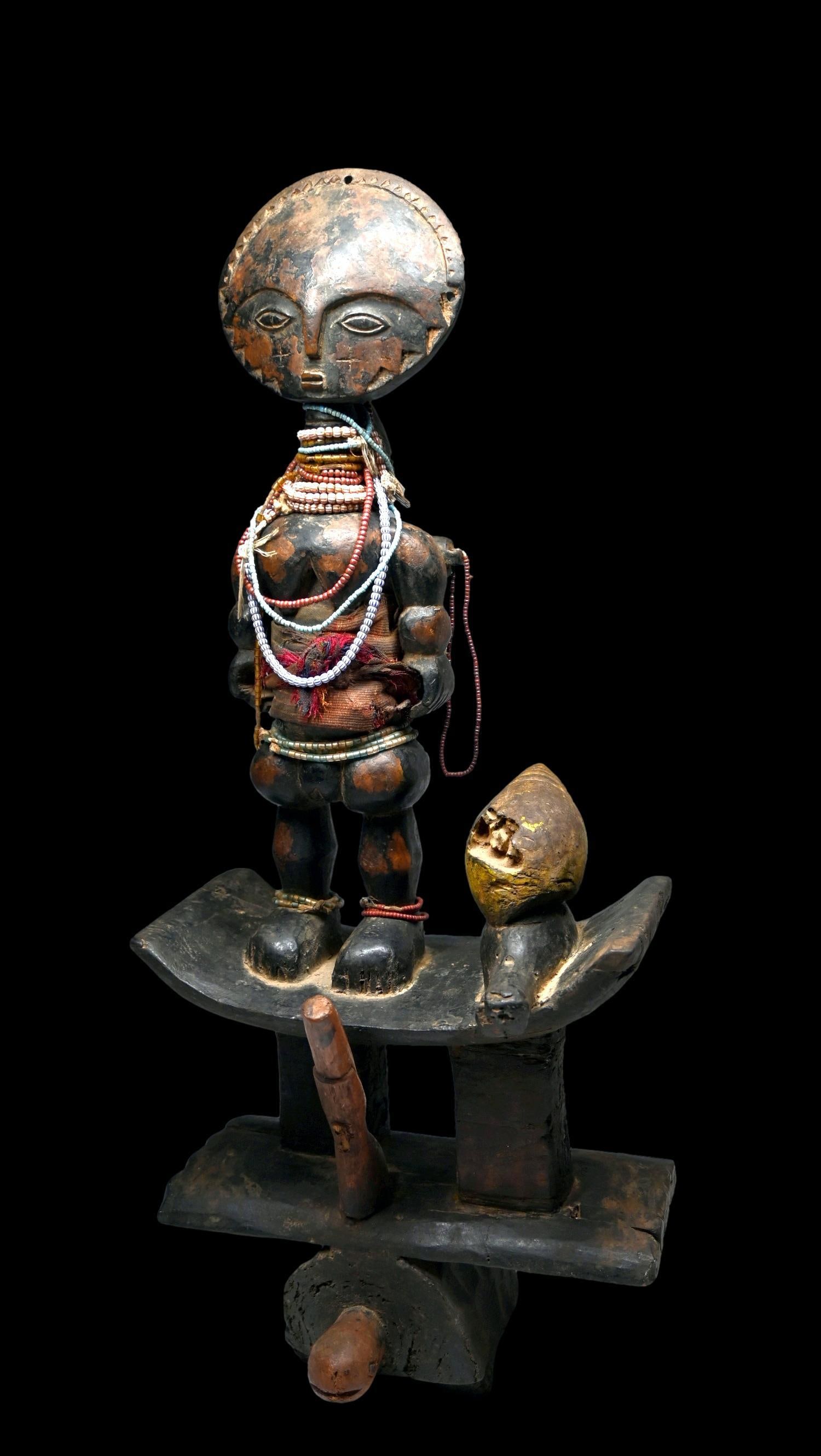 Ashanti Shrine Sculpture with Snail, Turtle and a Rifle: A carved wooden shrine effigy with wonderful symbology and well weathered and worn surface. The Shrine idol features an anthropomorphic figure atop a royal stool that resembles an akua'ba doll or fert