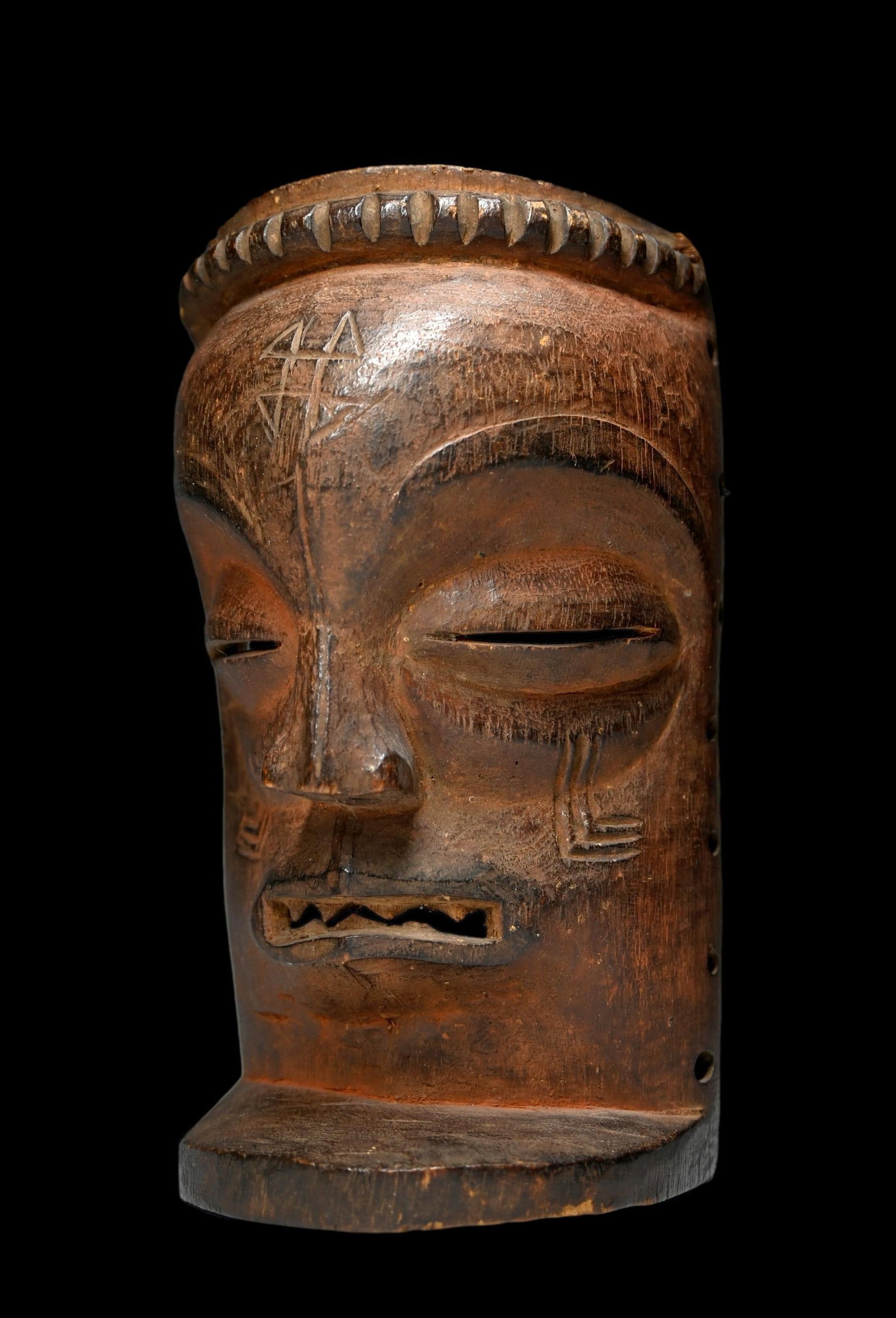 A Chokwe Male Mask: A carved wooden mask known as Chihongo which represents a male spirit and refers to wealth and power. This mask would have only have been worn by a high-ranking member of society or his sons during pr
