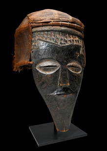 A Kuba Lele Dance mask: A Carved wooden ceremonial mask with wonderful geometric designs, large oval eyes accented with grayish kaolin clay pigments, elongated chin and attached headdress from rattan and woven grasses. Such