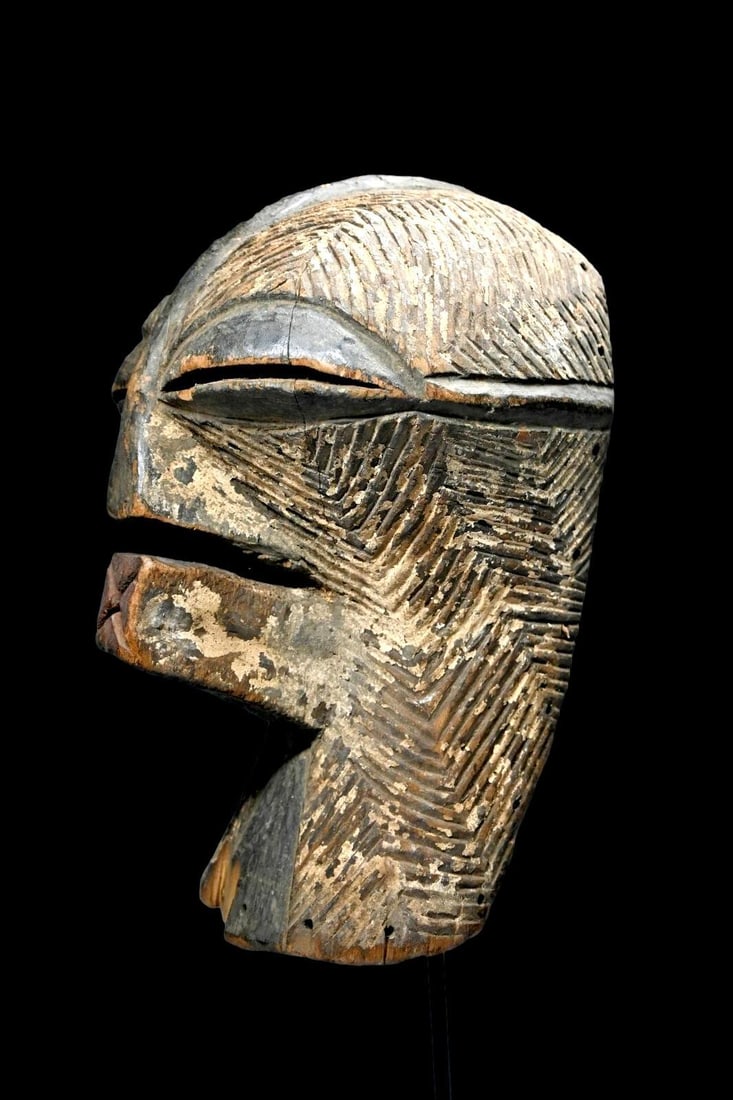 A Songye Kifwebe Female Dance Mask: A wooden ceremonial dance mask with contrasting black and white painted linear designs and wonderfully stylized face and form. The interior has a stained surface, worn smooth from handling, many attac