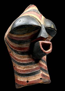 A Songye Mask Ex Barthels: A wooden ceremonial dance mask with contrasting black, red and white painted linear designs and wonderfully stylized face and form. The interior has a stained surface, worn smooth from handling, many