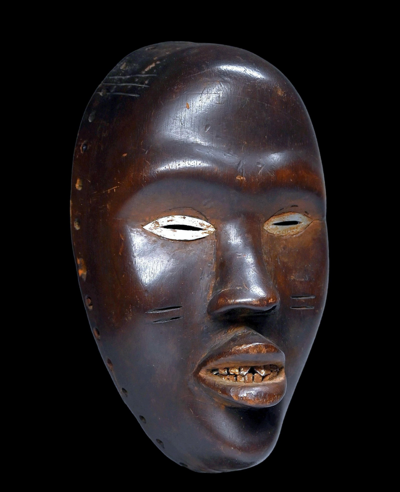 A Fine Dan African Mask: A very finely carved wooden ceremonial mask with relaistic facial features, some incised linear scar designs, inset metal teeth as well as hammered aluminum around the eyes. The mask measures 9.5 x 5.