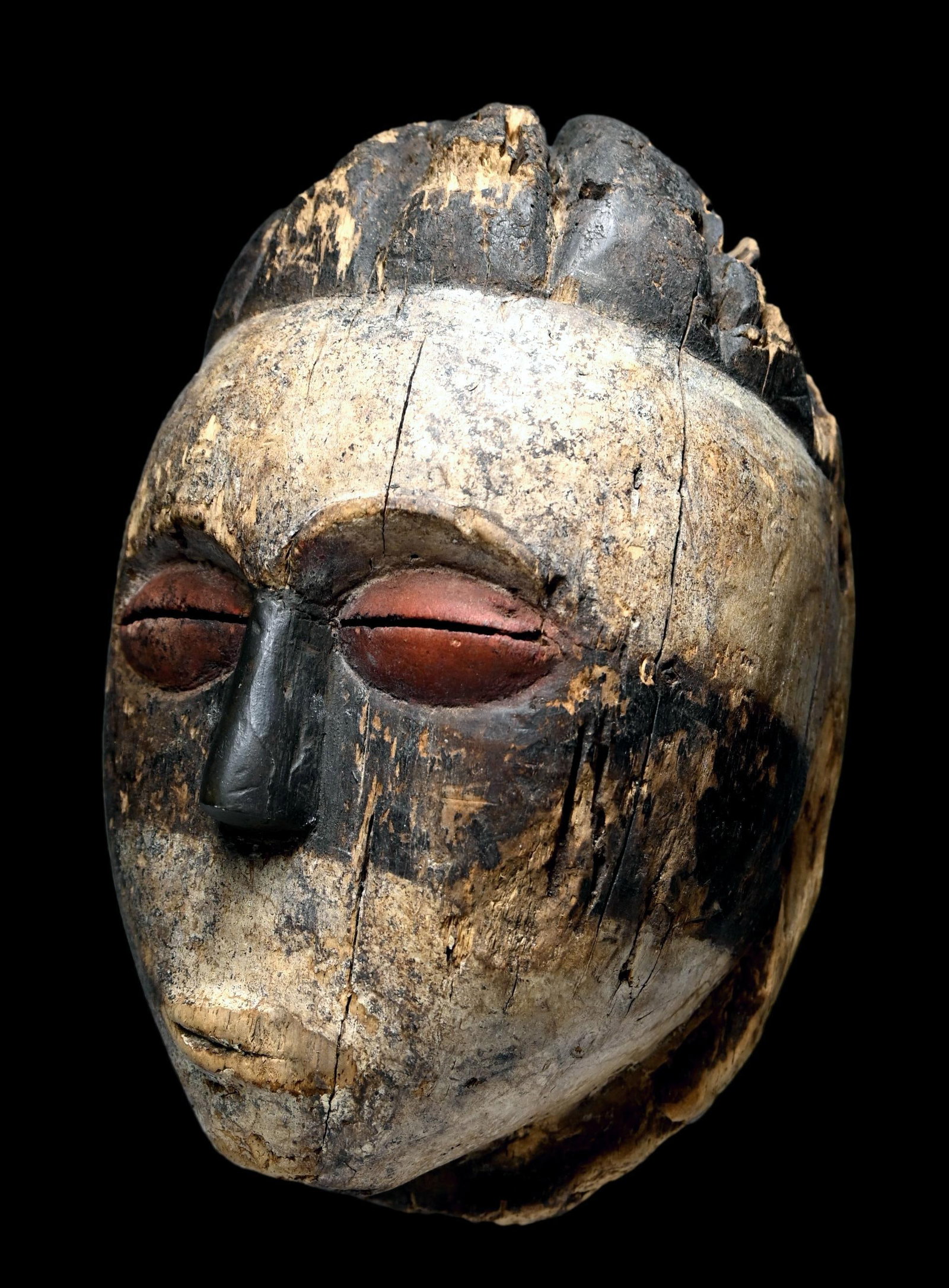 A Goloa mask Ex Banks: A carved wooden ceremonial mask painted with kaolin clay and organic pigments was likely used in rituals of the Bwiti Cult. The mask is eroded and weathered, yet what remains is a striking example. Th